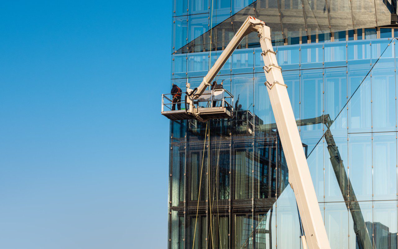 A man in a cherry-picker is working on the side of a building.