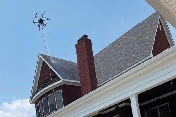 A drone flying near a house chimney on a clear day.