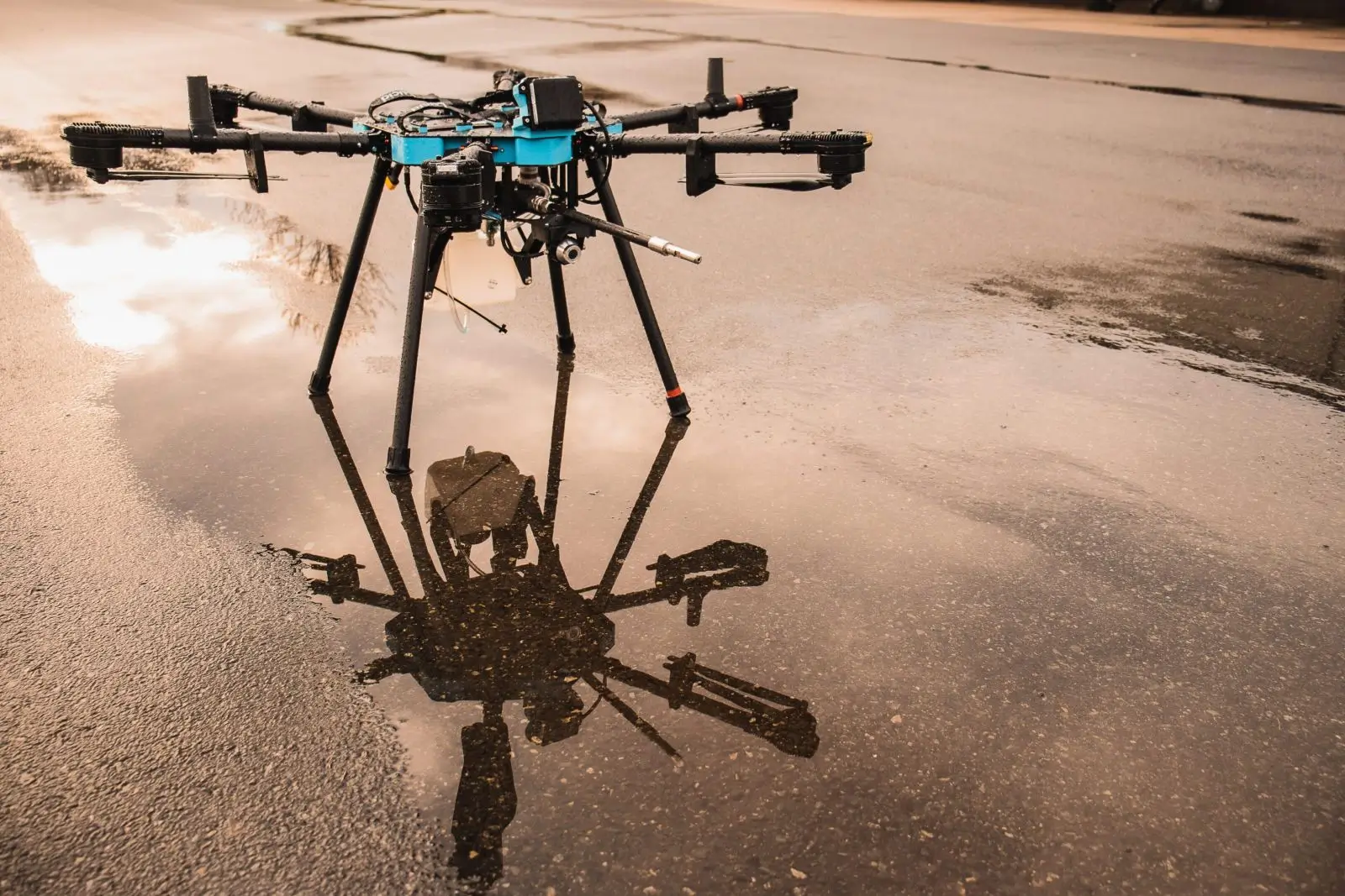 A drone with eight rotors standing on wet ground, casting a clear reflection.